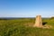 A concrete trig point on Ditchling Beacon with a blue sky overhead