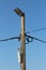 Concrete utility pole with multiple electrical wires and camera with cell phone tower transmitter and large light reflector on top