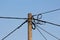 Concrete utility pole with multiple electrical wires connected on clear blue sky background