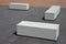 Concrete white park bench block shape on dark paving square, clean cast concrete surface gray brown white light barrier against