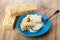 Condensed milk poured on broken puffed rice, spoon in saucer, puffed rice on table