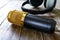 Condenser gold microphone and headphones lies on a wooden table.