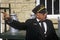 A conductor stands in front of an old standard gauge steam engine car holding antique milk cans in Eureka Springs, Arkansas