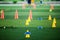 Cone markers is soccer training equipment on green artificial turf with blurry kid players training background