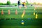 Cone markers is soccer training equipment on green artificial turf with blurry kid players training background