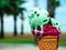 Cone of pistachio raspberry ice cream on a beach