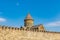 The cone-shaped dome of the Svetitskhoveli temple in Mtskheta, against the blue sky, behind the crenellated fortress wall