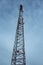 Cone-shaped metal mobile communications tower cell site against the sky at dusk. Vertical orientation.