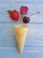 Cone wafflefor ice cream, fruit strawberry, refreshment pattern creative rose flower pattern on a blue wooden