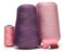 Cones and spools of pink purple violet sewing threads on white background