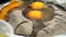 A confectioner adding several eggs into a bowl full of flour