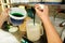 Confectioner in chef uniform is adding mint essence with spatula. Woman adds a mint extract and a concentrate to ice cream.