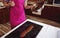 Confectioner chocolatier wearing pink apron pouring melted chocolate on marble surface on the background of wooden kitchen