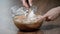 A confectioner cooks a dough. A hand with a plastic spatula stirs the dough in a bowl for baking a chocolate biscuit cake.