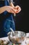 Confectioner cracking an egg into steel dish