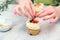 Confectioner decorate cupcakes with cream cheese and berries, close up. Homemade pastry. Woman cooking cakes