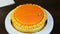 Confectioner decorate with edible gold leaf orange glazed round sponge cake