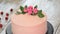 Confectioner decorates pink cake with roses. Series.
