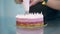 Confectioner decorates three-layer round cake with cream