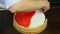 Confectioner by hands decorating round glazed cheesecake by shortbread border