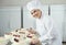 Confectioner is holding a cake in her hand in the bakery.