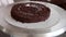 confectioner impregnating chocolate sponge layer of cake with chocolate syrup