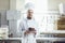 Confectioner man holding cake smiling in a pastry shop