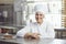 Confectioner with pastry cake in his hand at the bakery.