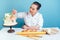 Confectioner pastry chef baker woman decorates creamy white two-tiered wedding birthday cake with fresh flowers on table