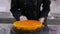 A confectioner pushes an orange cake to the front of the cameras frame