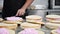 Confectioner puts cream to top of cake. Baker smoothing cake with whipped cream icing at confectionery.