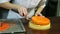 Confectioner puts round orange glazed cheesecake on almond interlayer