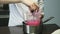 Confectioner quickly stirs homemade pink liquid glaze in plastic pail