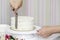 The confectioner`s hands decorate the cake with white cream