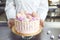 Confectioner`s hands hold a pink cake