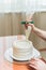 confectioner squeezes the cream on the cake. Girl making a cake.