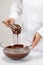 Confectioner whisking melted Belgian chocolate in glass bowl using wire whisk