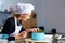 A confectioner woman decoration a cake in kitchen.