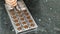 Confectioner woman is putting chocolate in mold on table in kitchen indoors.