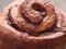 Confectionery baking. Sweet fresh soft roll bun with cinnamon on wooden background. Cinnabon closeup