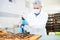 Confectionery factory worker decorating pastry using icing bag