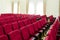 Conference hall with red comfortable chairs and beige walls with curtains on the windows