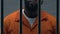 Confident African-American head of mafia standing in prison cell, criminal