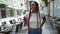 Confident african american woman, beaming with joy, casually standing on sunlit coffee shop terrace in an urban city