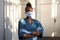 Confident african nurse wear blue uniform, face mask, standing in hospital.
