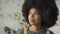 Confident African woman with Afro hair looks at camera indoors, headshot.