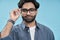 Confident arab young man wearing eyeglasses isolated on blue background.