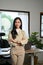 Confident Asian businesswoman arms crossed, looking at camera, standing in her office