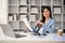 Confident Asian businesswoman sits at her desk in her private office with business reports