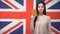 Confident Asian woman showing passport against British flag background, emigrant